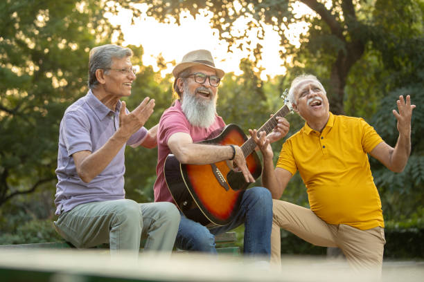 istock Older friends playing guitar and enjoying in park 1911481939