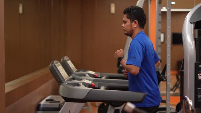 Young Asian men athlete running or jogging on treadmill in a hotel sport club
