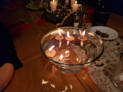 traditional Christmas table with a metal tree and candles spins the merry-go-round with hot air. tinkling carillon. dropping a candle shell in a bowl of water is a tradition, tinkling, carlion