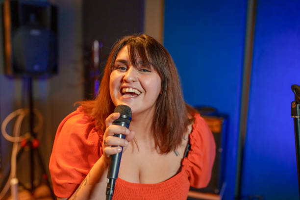 istock Young woman singing with a microphone in a music studio. 1911508283