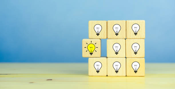 istock Creative idea, New idea, innovation and solution concept. wooden cubes with the yellow light bulb symbol on table, blue background, copy space 1911525144