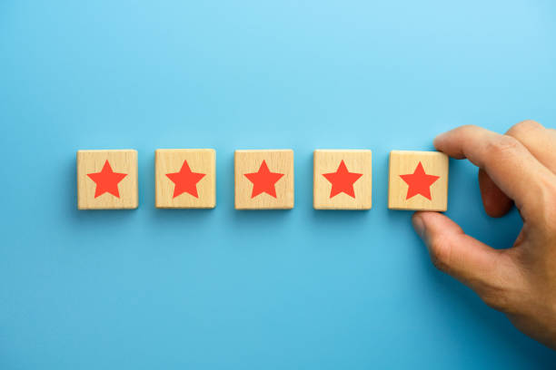 istock Customer experience, satisfaction survey, Evaluation, Increase rating and best excellent services rating concepts. The client's hand picked the five star symbol on wooden cubes on blue background. 1911526190