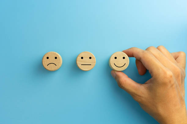 istock Customer service evaluation and satisfaction survey concepts. The client's hand picked the happy face smile face icon on wooden cube on blue background. copy space 1911526208