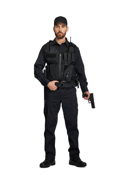 istock Handsome policeman posing with weapon in hand in studio. 1911537622