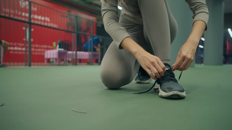 Sporty young Asian woman sitting to tie shoelace before jogging and running on sky running track on high building in city, Active lifestyle with exercise activities, Outdoor fitness at night