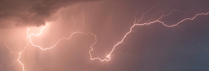 beautiful lightning during a thunderstorm at night in a forest that caused a fire, against a dark sky with rain