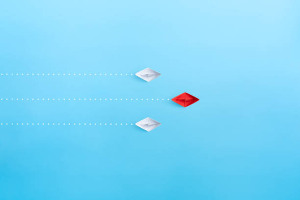 istock Leadership concept with red paper ship leading among white on blue background, minimal, copy space 1911581061