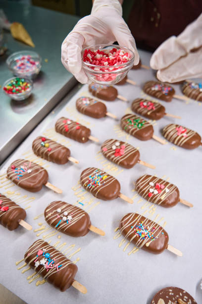 istock Pastry chef busy with decorating cakesicles on worktop 1911584208