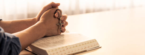 Male folded hand prayed on holy bible book. Blurring background Burgeoning.