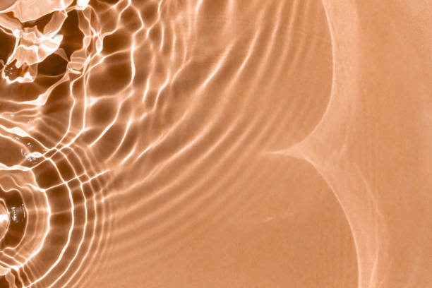 istock Textured background of rippled peachy water with solar lightning 1911595368