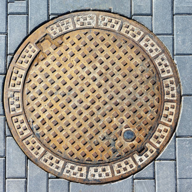 istock city sewer manhole cover between blocks, top view 1911595884