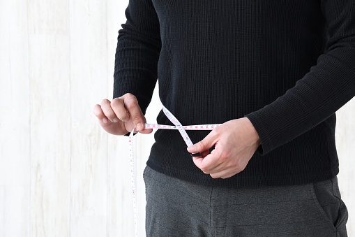 Man measuring stomach with tape measure