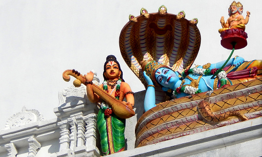 HYDERABAD,INDIA-SEPTEMBER 12,2017: View of Indian Hindu God Vishnu sleeing on sesha naga or snake and narada statues on temple tower