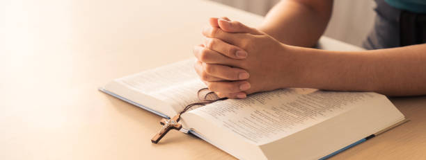 istock Male folded hand prayed on holy bible book. Blurring background Burgeoning. 1911602520