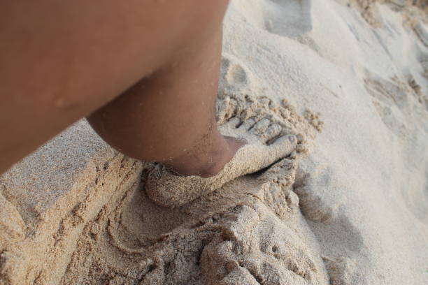 istock left foot playing on the beach sand 1911606327