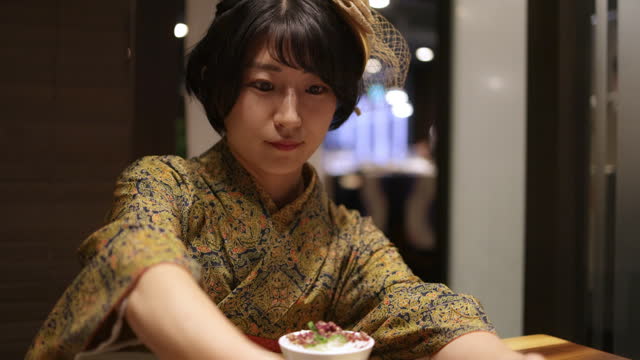 Young woman in Kimono / Hakama serving a dish in Japanese restaurant - slow motion