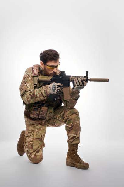 istock Brave male soldier with machine gun aiming, shooting from knee. 1911609065