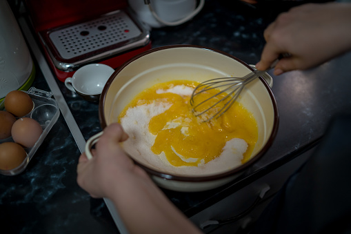 young woman in a gray aprons breaks the eggs.