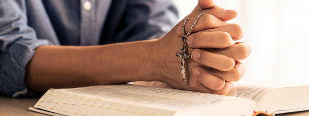 istock Male folded hand prayed on holy bible book. Blurring background Burgeoning. 1911613834