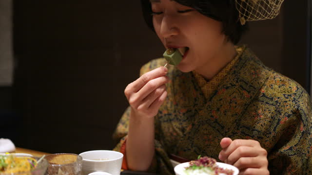 Young woman in Kimono / Hakama eating food for lunch in Japanese restaurant