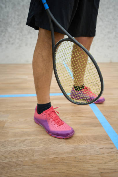istock Man in black sweatpants and sneakers holding squash racket 1911636430
