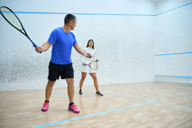 istock Man instructor fervently teaching woman to play squash exercising 1911636945