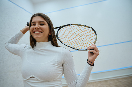 Elegant and athletic lady playing squash skillfully handling racket on indoor court
