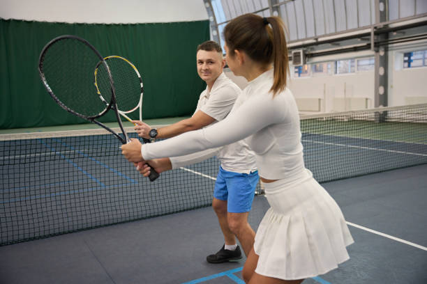 istock Athletic woman with man instructor play tennis improving skills learning to hit 1911637568