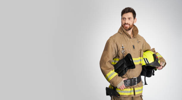 istock Attractive male firefighter posing with hand on belt in studio. 1911641205