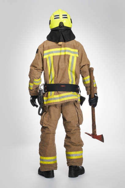 istock Unrecognizable male firefighter in uniform holding fire axe in studio. 1911642763