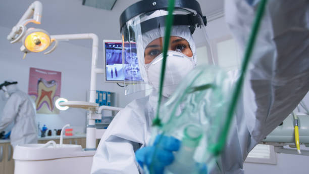 istock Dentist in coverall leaning over patient putting oxigen mask 1911645387
