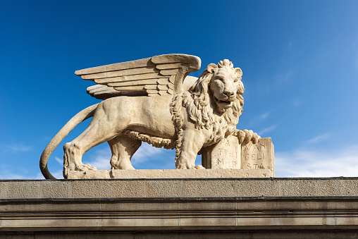Statue of the Winged Lion of Saint Mark, symbol of the evangelist, the Venetian Republic and the Veneto Region. Freedom square (Piazza della Liberta), Udine, Friuli-Venezia Giulia, Italy, Europe.