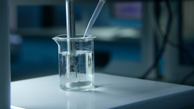 Rotating substance in glass of liquid in laboratory. Stock footage. Chemical experiment with substance and liquid in flask. Professional chemical experiment in laboratory.