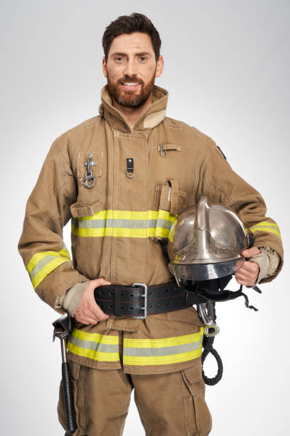 istock Strong male firefighter in uniform with helmet in studio. 1911672226
