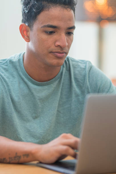 istock Smiling young man freelancer using laptop studying online working from home, happy casual hipster guy typing on pc notebook surfing internet looking at screen enjoying distant job sit at table 1911683240