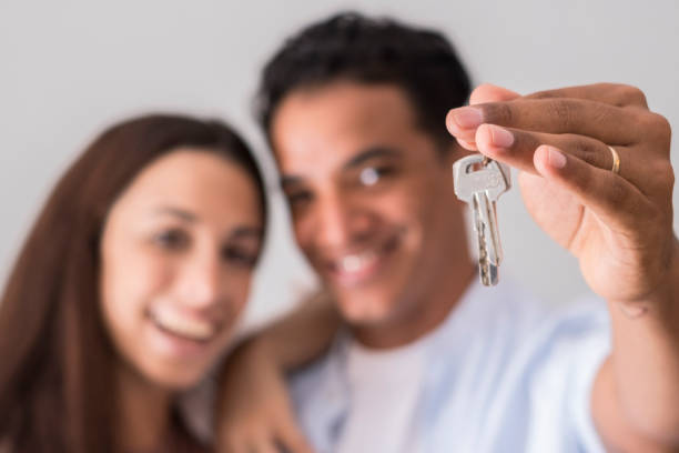 Close up of new home keys and young interracial couple smile and show the property - new life mortage house buyers people concept - happy youth family in love and relationship showing key primer plano de las llaves de la casa nueva y la sonrisa de la pareja interracial joven y muestra la propiedad - concepto de personas de los compradores de la casa de la hipoteca de la nueva vida - familia joven feliz en el amor y la relación que muestra