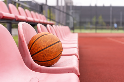 Used basketball in the foreground lies on an empty basketball court with a blurred background. High quality photo