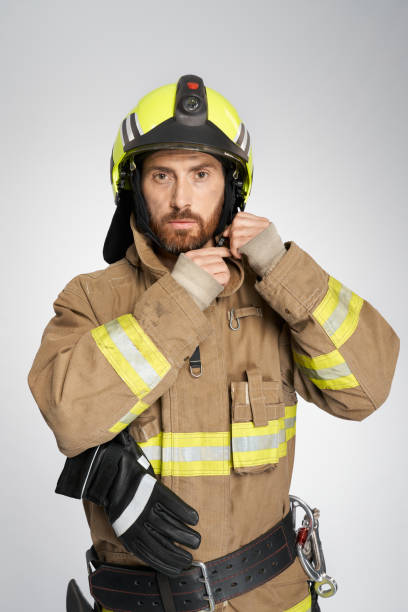 istock Serious male firefighter fastening protective helmet for work. 1911699418