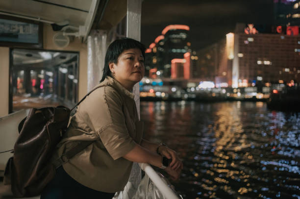 asian chinese mature woman taking star ferry crossing hong kong island to kowloon at night - sailing light wind nautical vessel imagens e fotografias de stock