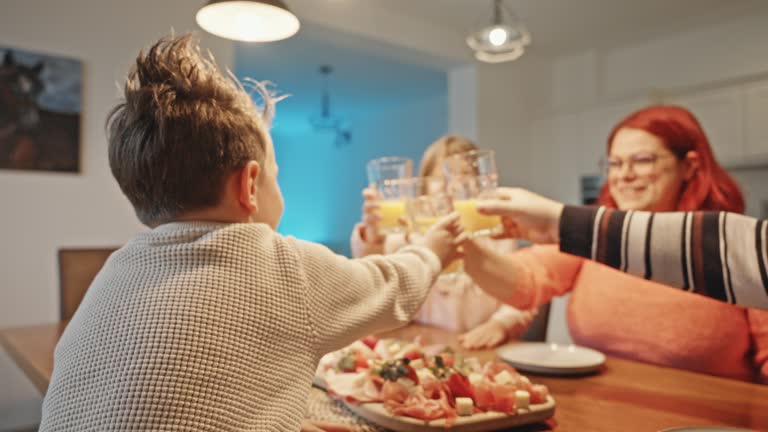 SLO MO Happy Parents and Children Toasting Juice Glasses while Having Lunch at Dining Table at Home