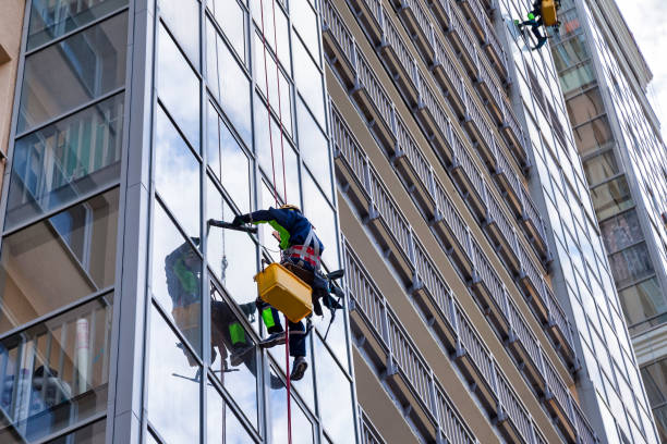 istock Two males worker during high-rise job washing glazing, rope access, hangs from build. Bottom view of industrial mountaineering men laborer in uniform. Industry urban works concept. Copy ad text space 1911768526