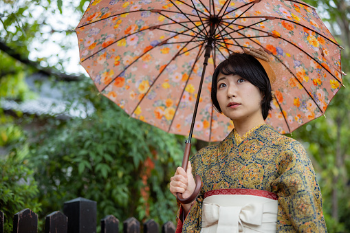 Young female tourist in Kimono / Hakama walking in Kyoto in a rainy day