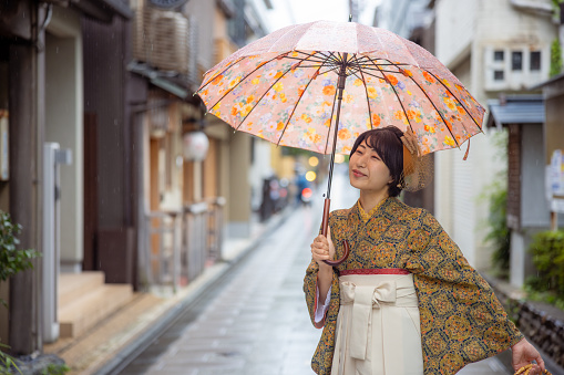 Happy young woman in Kimono / Hakama walking on traditional Japanese town in Kyoto