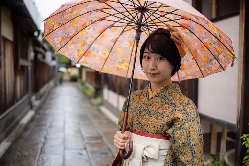 Portrait of young woman in Kimono / Hakama standing on traditional Japanese street in Kyoto