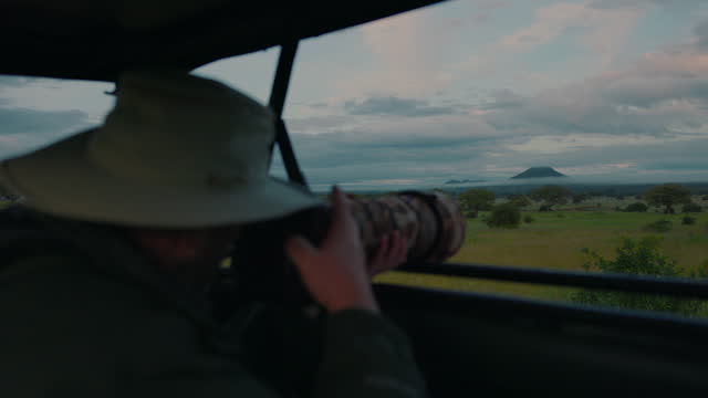 Tourist captures Tarangire's scenic view from vehicle. Safari photographer in Africa