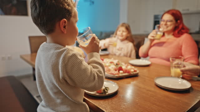 SLO MO Cute Boy with Family Toasting Juice Glasses while Having Lunch at Dining Table at Home