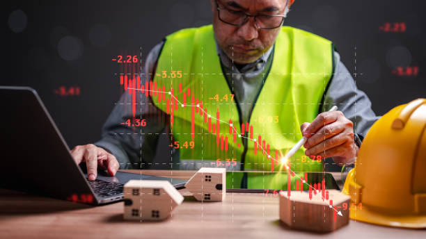 istock Stocks fall, stressed by stock losses, Engineer analyzes statistics and graphs, confronting potential bankruptcy, emphasizing challenges of simultaneous investments in both housing market business 1911794582