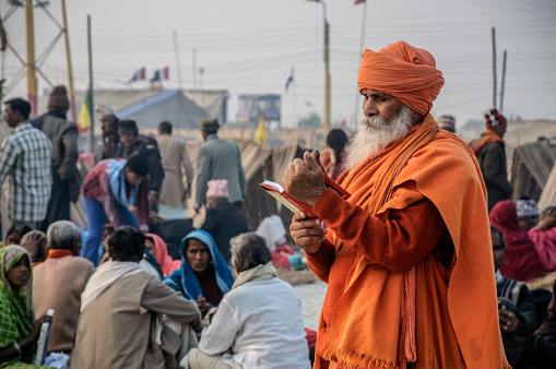 South 24 parganas, west Bengal, India. An Indian monk reading religious book at a religious fair at Gangasagar in an afternoon.