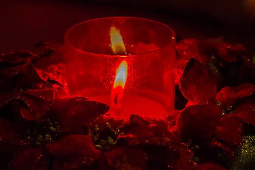 A glowing, burning candle in a dark background.