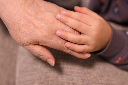 Close up image of Grandmother and grandson holding hands together